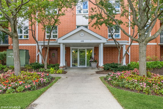 Front view of an apartment building entrance with a brick exterior and a small canopy above the door.