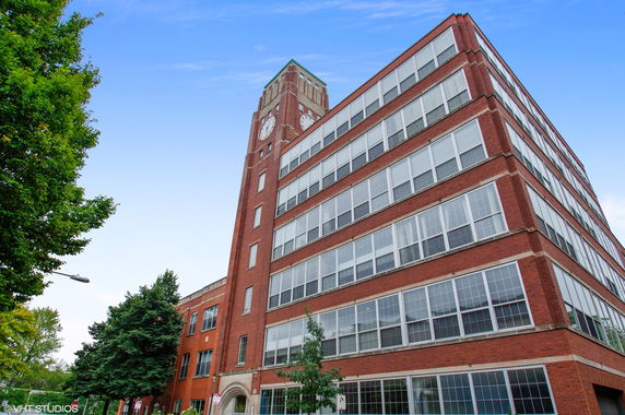 Front view of a multi-story brick building with a clock tower.