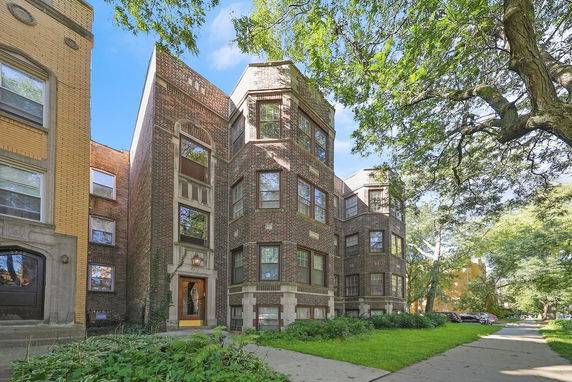 Front view of a multi-story brick apartment building with large windows.
