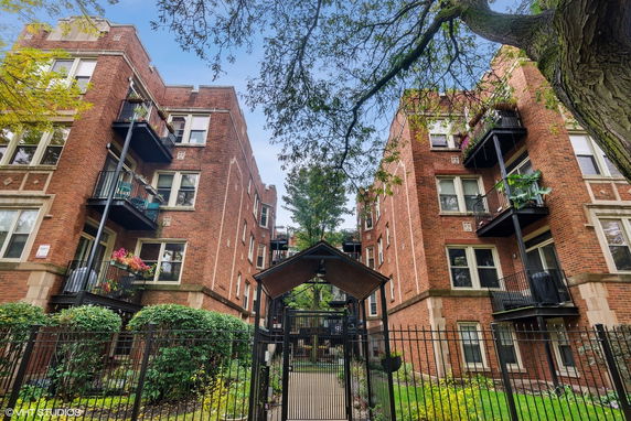 Front view of a multi-story brick apartment building with balconies.