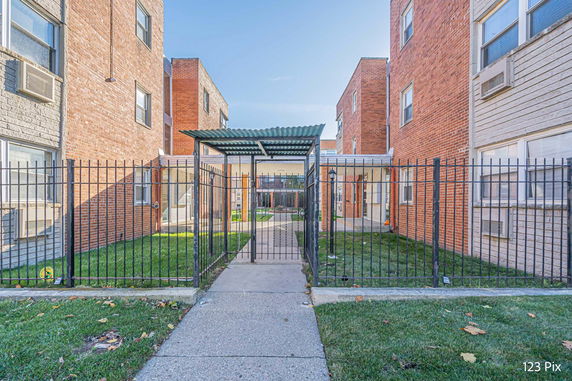 Front view of a multi-story brick apartment building with a gated entrance.