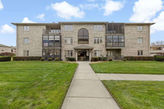 Front view of a three-story brick apartment building with a central entrance.