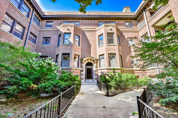 Front view of a brick apartment building with prominent bay windows and ornate entrance.