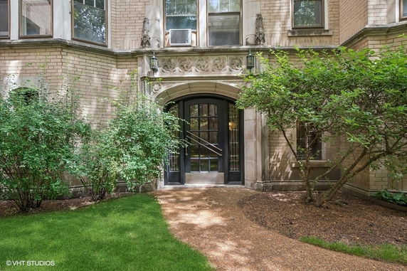 Front view of a building entrance with decorative stonework and large windows.