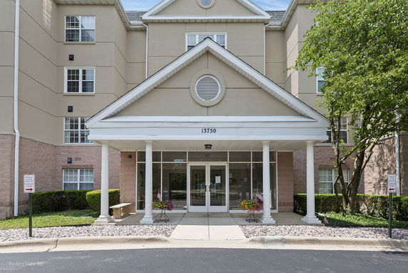 Front view of a multi-story building with a covered entrance and glass doors.
