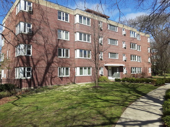 Front view of a brick apartment building with multiple floors and several windows.