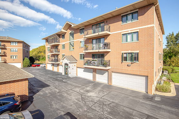 Front view of a multi-story brick apartment building with balconies and garages.
