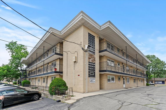 Front view of a three-story apartment building with balconies and parking area.