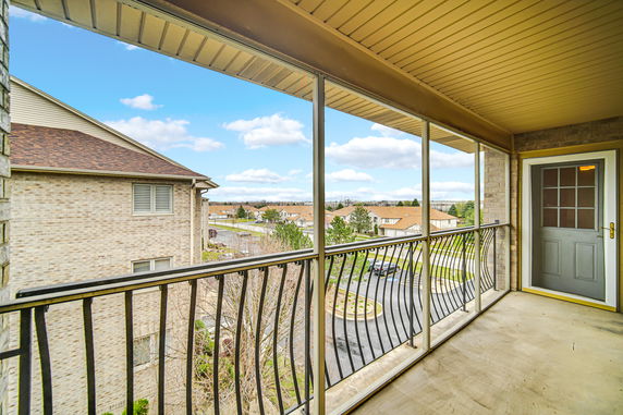 Panoramic view from a balcony overlooking residential area with houses and trees.