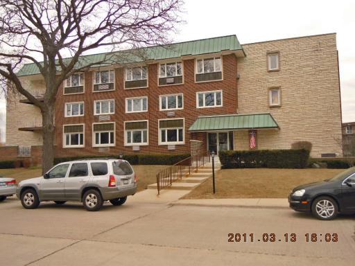 Front view of a three-story brick building with a green roof.