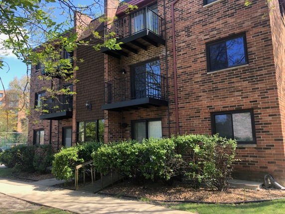 Front view of a multi-story brick building with balconies.