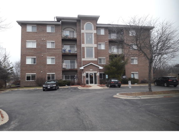 Front view of a multi-story brick apartment building with balconies.
