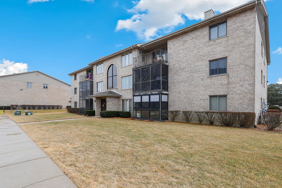 Front view of a three-story apartment building with brick exterior and balconies.