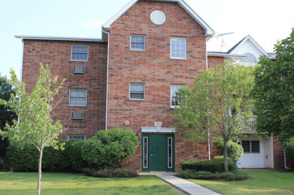 Front view of a three-story brick apartment building with green door.
