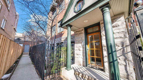 Exterior view of a house with stone facade and green columns.