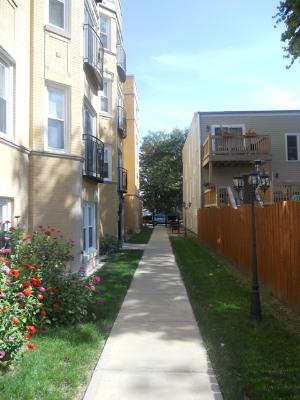 View of a walkway between two multi-story buildings with balconies.