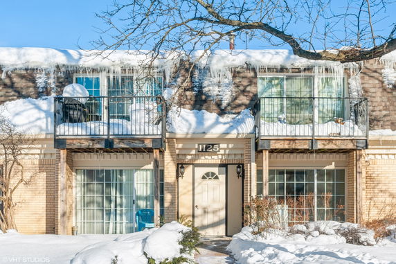 Front view of a two-story house with snow-covered balconies and icicles.
