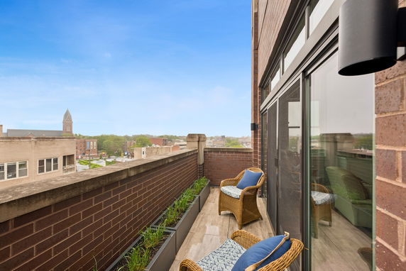Balcony with wicker chairs and view of surrounding buildings.