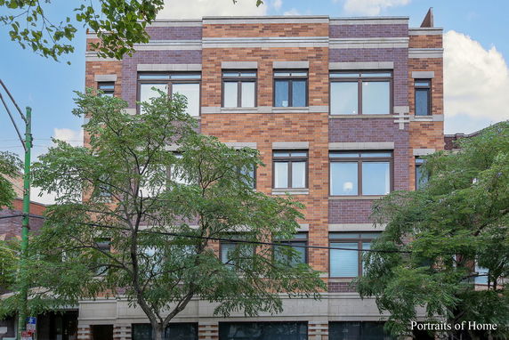 Front view of a multi-story brick building with large windows.