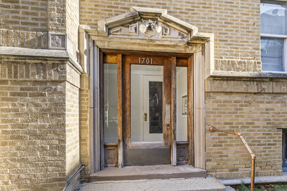 Front view of a brick building entrance with wooden door and address number 1701.