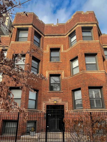 Front view of a multi-story brick building with bay windows.
