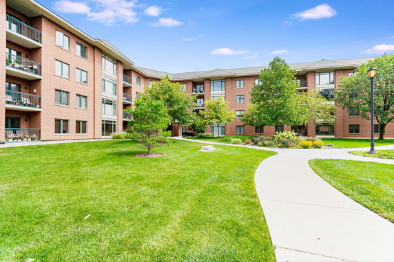 Front view of a multi-story brick apartment building with balconies.