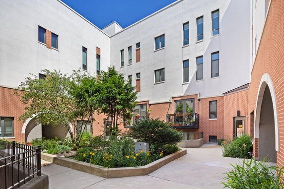 Exterior view of a multi-story building with a courtyard and plants.