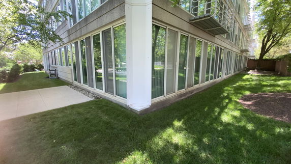 Front view of a multi-story building with large glass windows and a grassy area.
