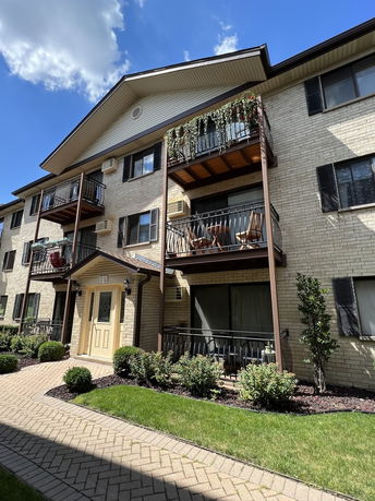 Front view of a multi-story residential building with balconies and brick exterior.