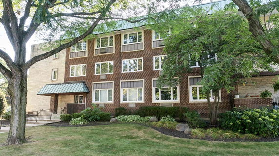 Front view of a multi-story brick building with numerous windows and a small entrance canopy.