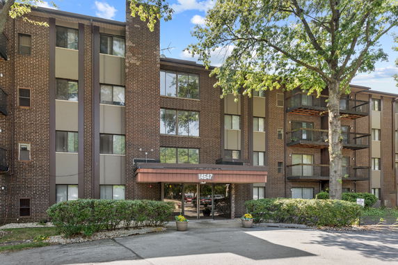 Front view of a multi-story brick apartment building with balconies.