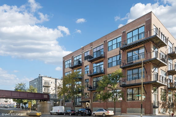 Front view of a multi-story brick building with large windows and balconies.