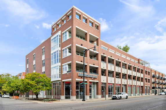 Front view of a multi-story brick building with balconies and large windows.