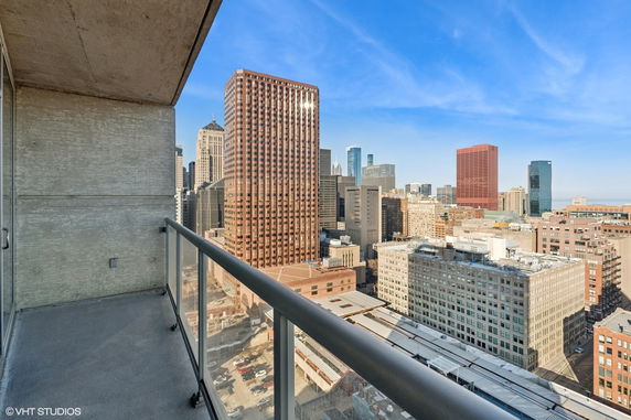 View from an outdoor balcony overlooking a city skyline with several high-rise buildings.