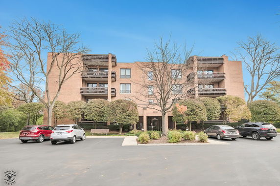 Front view of a multi-story apartment building with balconies and parking area.
