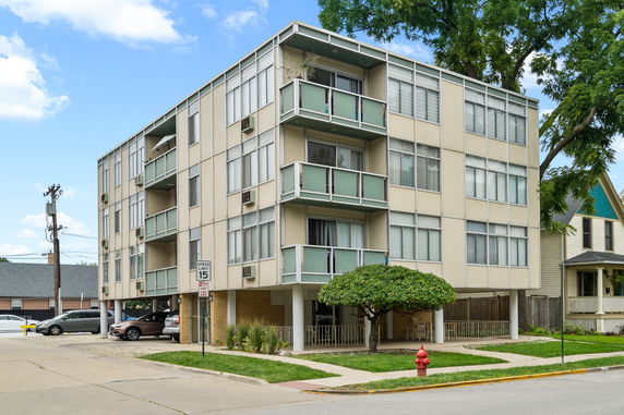 Front view of a three-story apartment building with balconies and large windows.