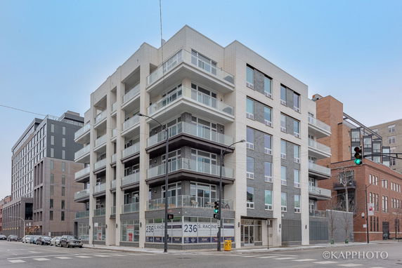 Front view of a multi-story apartment building on a street corner.