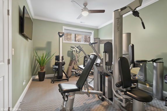 Indoor gym area with exercise equipment and a wall-mounted TV