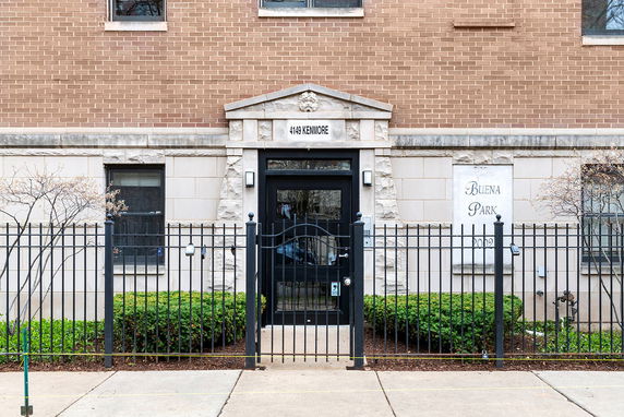 Front view of a brick building with a black metal fence and entrance labeled '4149 Kenmore'.