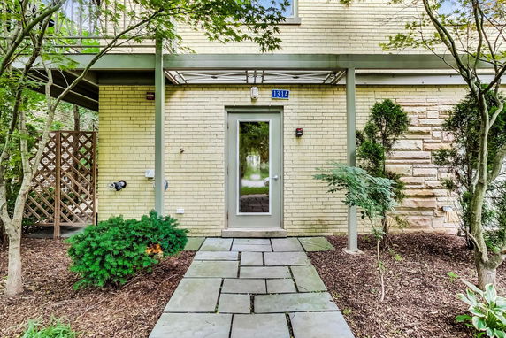 Front view of a building entrance with a glass door and surrounding vegetation.