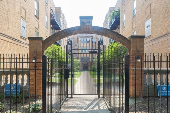 Front view of a brick apartment building with a gated entrance.