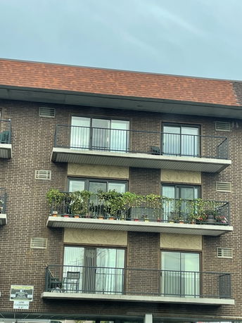 Front view of a multi-story brick apartment building with balconies.