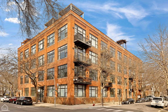 Front view of a red brick multi-story residential building with balconies.