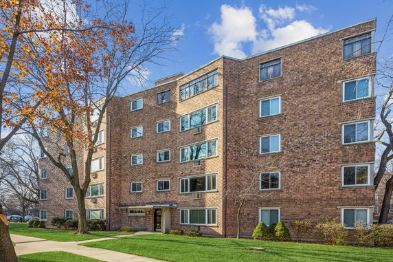 Front view of a multi-story brick apartment building with several windows.