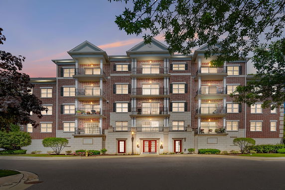 Front view of a multi-story residential building with a brick facade and balconies.