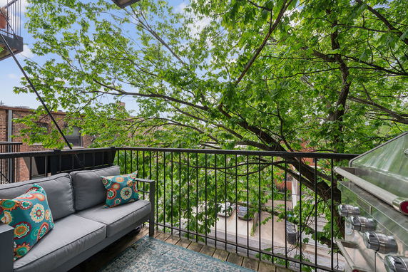 View of surrounding areas from an outdoor balcony with a sofa and grill.