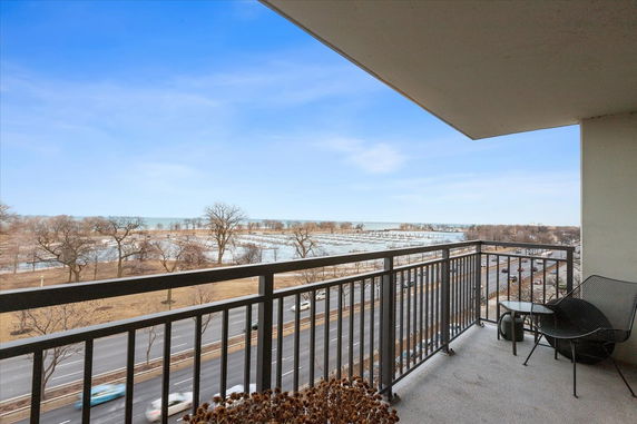 View from a balcony overlooking a road and a large body of water in the distance.