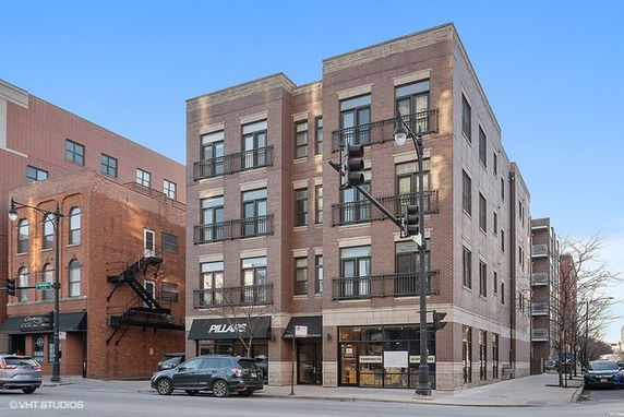 Front view of a four-story brick commercial building on a street corner.