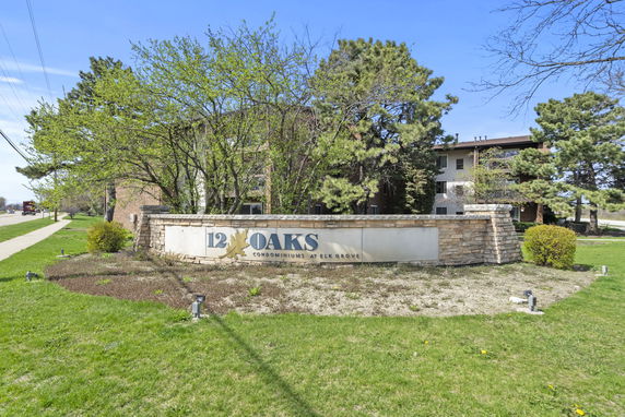 Front view of a condominium building with a sign reading '12 Oaks Condominiums'.