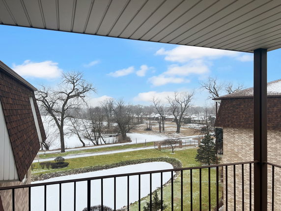 Panoramic view from a balcony overlooking a snowy landscape with trees and adjacent buildings.